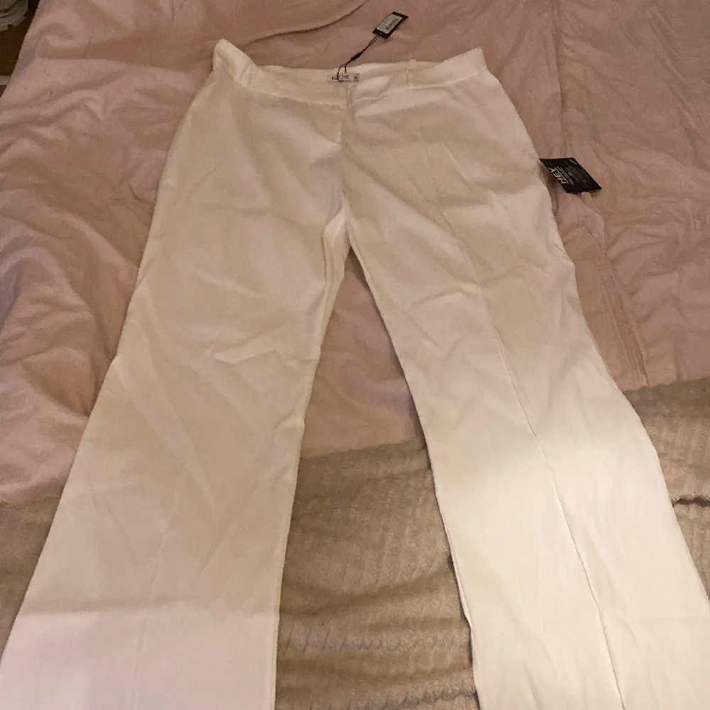 Helt oanvända vita kostymbyxor som är low waist och har ett litet utsväng nere vid benen . Jeans & Byxor.