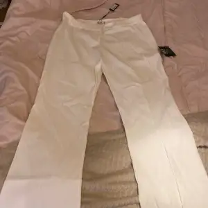 Helt oanvända vita kostymbyxor som är low waist och har ett litet utsväng nere vid benen 