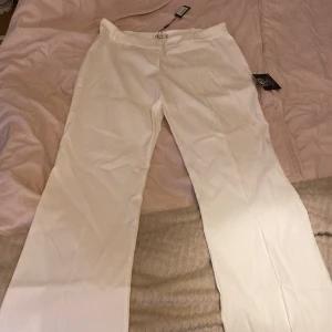 Kostymbyxor  - Helt oanvända vita kostymbyxor som är low waist och har ett litet utsväng nere vid benen 