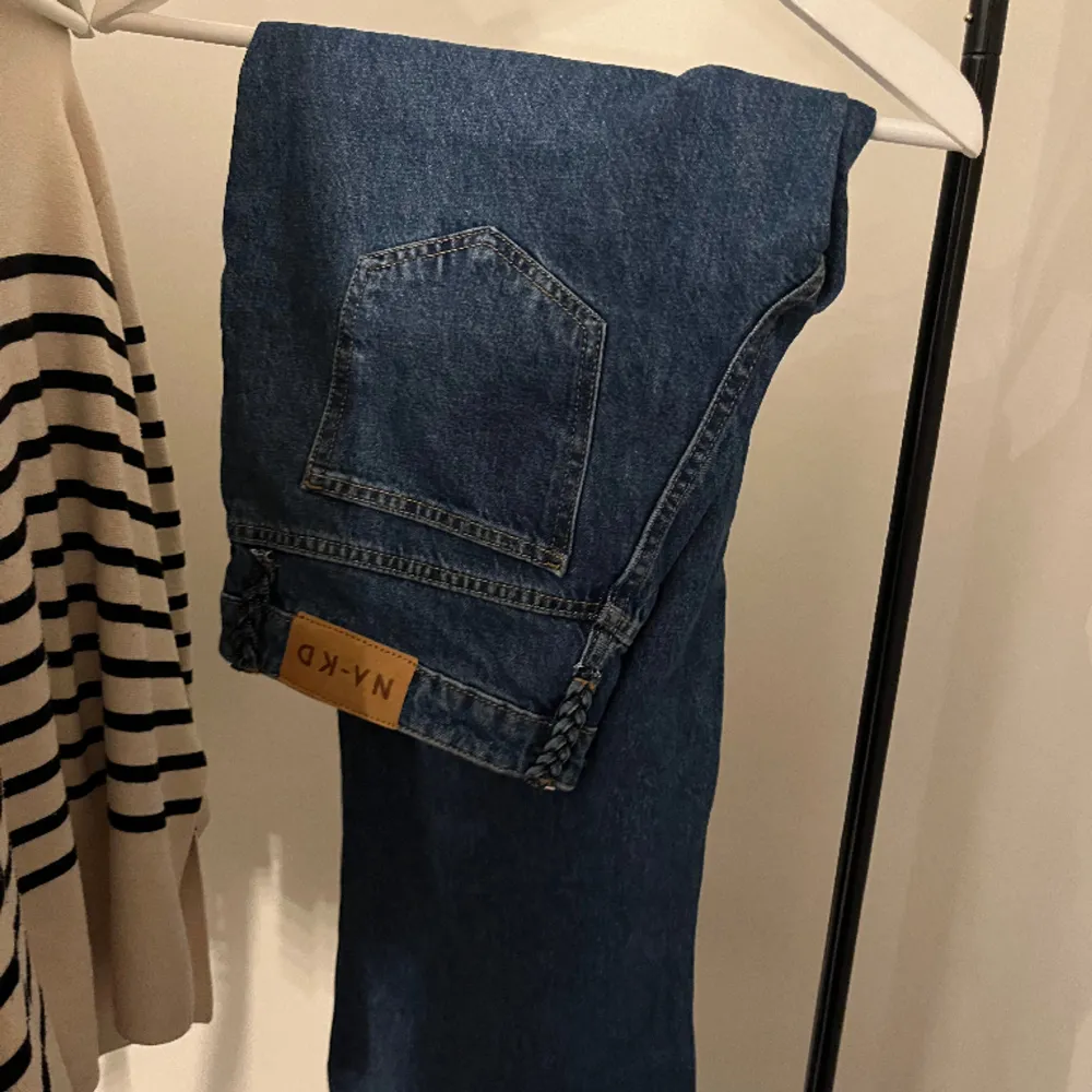 Ett par mörkblåa, medelmidjade jeans från nakd, aldrig använda! Vida i benen och har fina detaljer där man kan ha bälte✨ Dem kan kännas lite större än storleken! Nypris 499. Kontakta mig vid fler bilder!. Jeans & Byxor.