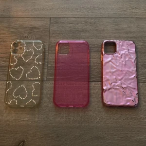 Tre snygga mobilskal i rosa och glitter iPhone 11 - Säljer tre olika mobilskal: ett transparent med glittriga hjärtan, ett transparent helrosa skal och ett metallic-rosa skal med skrynklig effekt. Perfekt för dig som vill variera stilen på mobilen och gillar rosa och glitter.