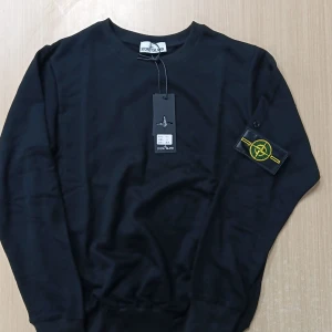 Svart sweatshirt från Stone Island S - Svart sweatshirt från Stone Island med klassisk rund hals och ikonisk logotyp-patch på ärmen. Tröjan är i mjuk bomull och har långa ärmar samt ribbade muddar. Perfekt för en clean och stilren look.