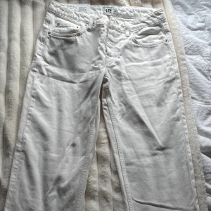 Vita straight leg jeans från Lager 157 - Säljer ett par vita jeans från Lager 157 med låg midja och raka ben. Klassisk femficksmodell med silverfärgade nitar och knapp. Snygg och enkel design som passar till allt. Helt nya och aldrig använda men har ett litet sträck på bakfickan som säkert går bort i tvätten. Skriv för fler bilder. 
