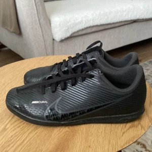  Nike Mercurial inomhusfotbollskor - Säljer ett par svarta Nike Mercurial inomhusfotbollskor, inget är sönder och är jätte sköna, och är andvända i 1 vecka.