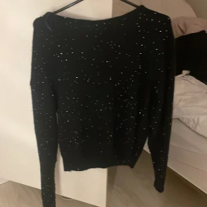 Svart glittrig tröja med öppen rygg andvänt typ en gång i storlek 158/164 - Svart långärmad tröja med glittriga detaljer över hela tyget och snygg öppen rygg. Perfekt för dig som vill sticka ut lite extra. Mjuk och stretchig, sitter snyggt på kroppen och passar till många olika outfits.