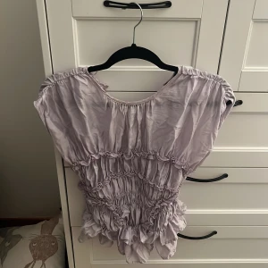 Ljuslila blus med volang från BikBok - Supersöt ljuslila blus från BikBok med volangdetaljer och rynkade partier. strlk S