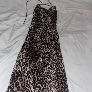 Leopardmönstrad långklänning med smala band - Supersnygg långklänning från zara med leopardmönster och smala axelband som korsas i ryggen. Klänningen har en figurnära passform och är tillverkad i ett mjukt, lätt material som känns skönt mot huden. Perfekt för dig som vill sticka ut med en trendig look. 