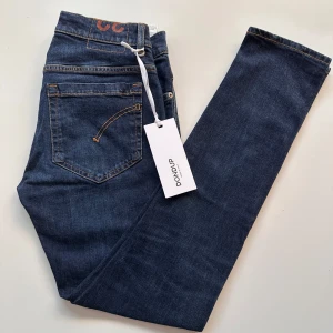 Mörkblå Dondup George jeans - Nya mörkblå jeans från Dondup med klassisk femficksdesign och orangea kontrastsömmar. Jeansen har knäppning med och är tillverkade i stretchigt material för en skön passform. Har legat i garderoben ett tag och blivit för små. Går att pruta osv men inga skambud tack.