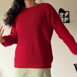 Röd stickad tröja med v-ringad rygg - Ribbstickad röd tröja med rund hals framtill och djup v-ringning i ryggen. Långärmad och i en loose passform, perfekt för lager-på-lager. Snygg och enkel att styla till både jeans och kjol. Kan använda med v-ringad sidan framtill också.