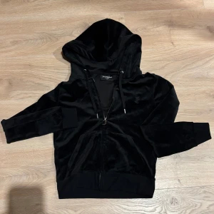 Svart velour hoodie Juicy Couture  - Svart hoodie i mjuk velour från Juicy Couture med dragkedja och huva. Tröjan har långa ärmar, snörning i huvan och en broderad J-logga på bröstet. Klassisk Juicy-dragkedja. Aldrig använd. 