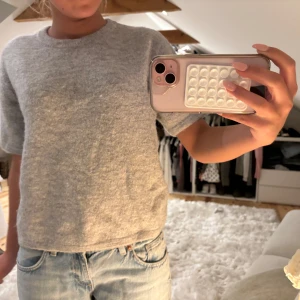 Grå stickad tröja med kort ärm - Mysig grå stickad tröja med korta ärmar och rund hals. Perfekt för lager-på-lager och passar till både jeans och kjol. Enkel och stilren design som funkar året runt.