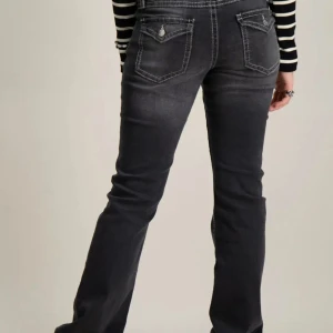 Svarta bootcut jeans med kontrastsömmar - Snygga svarta jeans med bootcut-modell och markerade vita kontrastsömmar. Jeansen har klassiska fem fickor, knapp och dragkedja framtill samt coola ficklock bak. Perfekta för dig som gillar en tidlös men edgy look.❤️