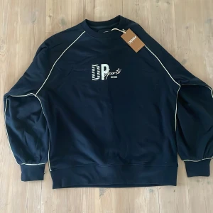 Mörkblå sweatshirt från Denim Project - Helt ny mörkblå sweatshirt från Denim Project med vita detaljer längs ärmarna och tryck på bröstet. Den är i storlek M men är stor i storleken