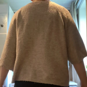 Beige stickad tröja med trekvartsärm - Mysig beige stickad tröja med rund hals och trekvartsärmar. Tröjan har en loose passform och är perfekt för lager-på-lager under höst och vinter. Enkel och stilren design som är lätt att matcha med olika outfits. Lite nopprig.