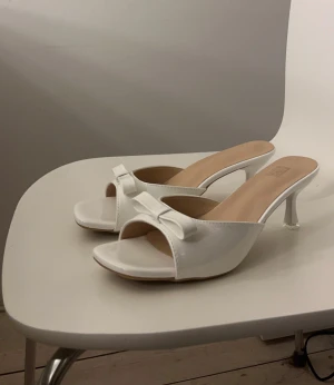 Vita klackar med rosetter - Vita klackar med öppen tå och en söta rosetter framtill. De är helt oanvända. Jag har vanligtvis storlek 39 och dem passar perfekt🫶