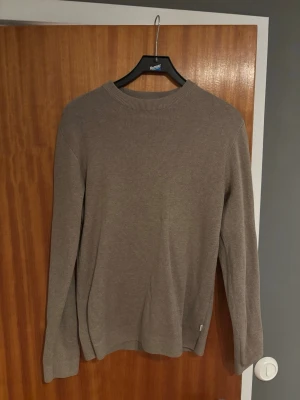 Beige stickad tröja från Jack & Jones - Säljer en beige stickad tröja från Jack & Jones Premium i storlek S. Tröjan har rund hals och långa ärmar med ribbade muddar. Enkel och stilren design som funkar till många olika outfits. Perfekt för dig som gillar klassiska plagg. Använd fåtal gånger. Priset går att diskutera!