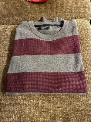 Grå och vinröd randig tröja Lindbergh - Snygg tröja från Lindbergh  i grått med breda vinröda ränder. Rund halsringning och mjukt material som känns skönt mot huden. Perfekt för dig som gillar stilrena och klassiska färgkombinationer. Passar till jeans eller chinos.