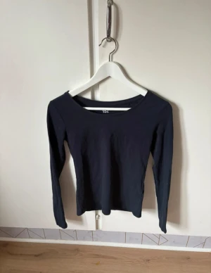 Marinblå långärmad topp  - En stilren Marinblå långärmad topp från Lager 157 i storlek XS. Toppen har rund halsringning och är tillverkad i mjuk bomull med lite elastan för skön passform. Perfekt att matcha med jeans eller kjol för en enkel och snygg look.