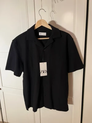 Svart kortärmad skjorta från Zara - Svart skjorta från Zara i storlek S med klassisk krage och korta ärmar. Skjortan är tillverkad i en mjuk mix av bomull och polyester. Perfekt till varmare dagar. Nypris: 300kr. Tveka inte att ställa frågor🤗