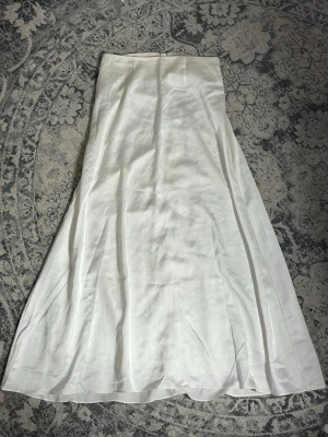 Vit långkjol i satin - Säljer en superfin vit långkjol i satin 🤍Kjolen har en enkel design med dragkedja i bak. Passar perfekt till sommaren och för dig som gillar minimalistisk stil