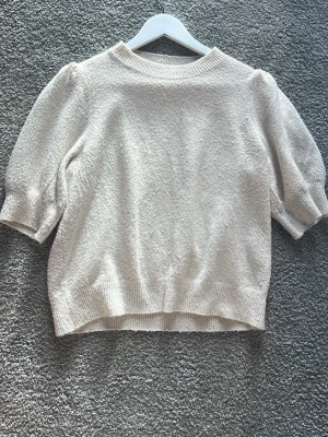 Beige stickad tröja Vero Moda M - Säljer en beige stickad tröja från Vero Moda i storlek M. Funkar till storlek S och L också. Tröjan har puffade korta ärmar och ribbade muddar vid hals, ärmslut och nederkant. Mjuk och skön struktur som passar perfekt under hösten och våren. En fin tröja som passar till allt tack vare den ljusa fräscha färgen. Har använts ett par gånger men säljer pga att den blivit för liten💕💕💕