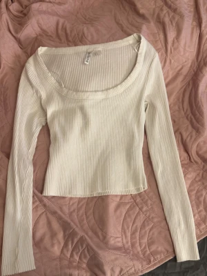 Ribbad vit långärmad topp från H&M - Säljer en ribbad topp i vit färg från H&M Toppen har lång ärm och rundad halsringning.