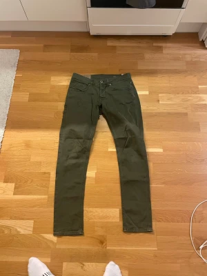 Mörkgröna Dondup byxor  - Säljer ett par mörkgröna Dondup George i storlek 34. Sitter mer som ett par 33. Byxorna har klassisk femficksdesign och är tillverkade i ett mjukt bomullsmaterial med lite stretch. Perfekt passform för dig som gillar smalare siluett.