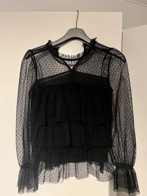 Svart blus  - Säljer en snygg svart blus med volanger från River Island