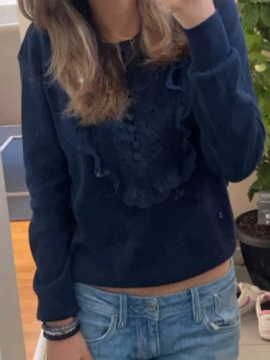 mördblå stickad tröja Holly & Whyte - ‼️Det var svårt att få med färgen så se på första bilden ‼️blå långärmad stickad tröja från Holly & Whyte med snygga spetsdetaljer och knappar framtill. älskar denna topp men den kommer inte till användning längre