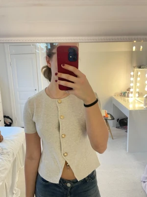 Beige kortärmad kofta med guldknappar - Säljer en beige kortärmad kofta i storlek S från SHEIN med snygga guldknappar framtill.