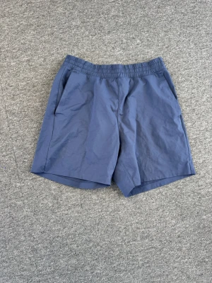 Uniqlo tränings Shorts - Snygga blå shorts med elastisk midja och sidofickor. De har en enkel och stilren design med en bakficka som har dragkedja. Perfekta för sommardagar och avslappnade tillfällen.