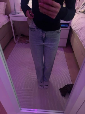 Ljusblå raka jeans - Säljer ett par ljusblå jeans med rak passform och hög midja. Jeansen har klassisk femficksdesign och är tillverkade i denim. Perfekta för en avslappnad och trendig look.