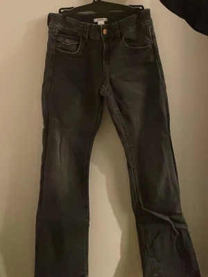 Mörkgrå bootcut jeans - Säljer ett par mörkgrå bootcut jeans, låg midja med brodering på fickorna. Storlek 164! 