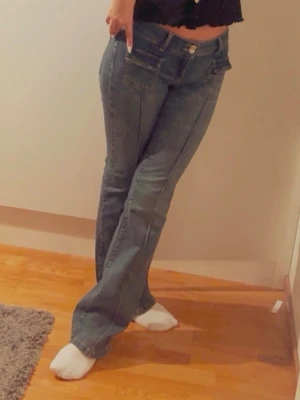 Blå bootcut jeans med låg midja - Snygga blå bootcut jeans med låg midja och klassiska fickor fram. Jeansen har en avslappnad passform och markerade sömmar längs benen. Perfekta för en trendig och avslappnad stil. Från nelly köpt för 699kr. 