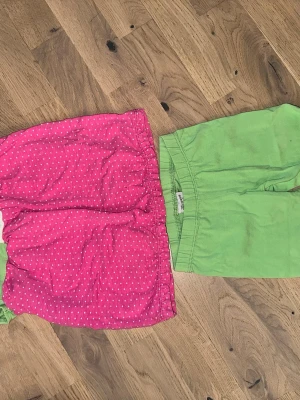 T-shirt och byxa set - Ett sött set med en grön tröja med kattansikte och en rosa prickig kjol. Tillhörande gröna byxor med rosetter vid bensluten. Säljer två par shorts, ett par rosa med vita prickar och ett par enfärgade gröna. Båda har resår i midjan och är perfekta för varma dagar. Sköna och lätta att bära, passar till det mesta