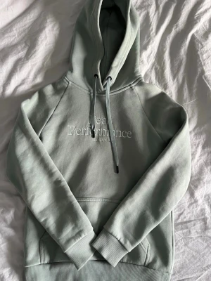 Ljus Grön hoodie från Peak Performance - Jag säljer en snygg ljusgrön hoodie från Peak Performance med vit logga på bröstet. Klassisk modell med huva, dragsnören och magficka. Mjuk bomullskänsla och bekväm passform. 