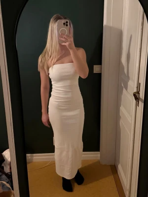 Vit bandeauklänning - Superfin vit bandeauklänning med slits. Klänningen är figurnära och har en snygg slits baktill.
