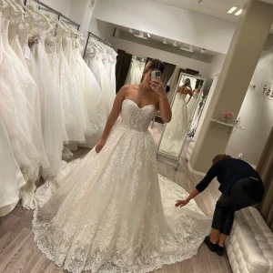 Vit lång brudklänning med spets - Säljer en fantastisk brudklänning i storlek 36-38 justerbar med snörning för perfekt passform. Klänningen är köpt från Stockholms Brud & Fest men har aldrig använts då den inte passade på grund av graviditet. Underkjol och slöja i matchande färg ingår. Nypris 50.000  Priset kan diskuteras vid snabbaffär :) 