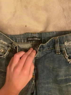 Dolge & Gabbana Jeans - Säljer ett par blå jeans från Dolce & Gabbana med slitna detaljer. Dessa jeans är ass snygga men tyvärr var dem förstora för mig. Dem har låg midja och är i straight/bootcut modell. Midjemåttet är ca 39cm (rakt över) och innerbenslängden är ca 82cm💗PRIS GÅR ATT DUSKUTERA, skriv prisförslag 💗