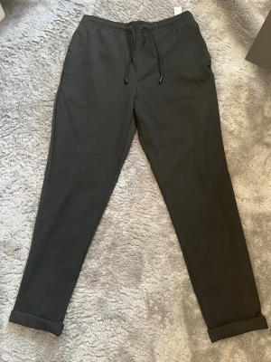 Svarta kostymbyxor från Zara - Svarta kostymbyxor från Zara med uppvikta benslut. Byxorna har två bakfickor och är tillverkade i ett mjukt och bekvämt material. Perfekta för en avslappnad stil.