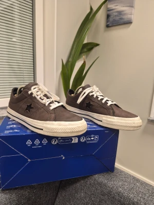 Rick Owens DRKSHDW x Converse One Star Pro sneakers i ett mörkt damm (brun/grå) skinn 38 - Säljer ett par bruna Converse One Star sneakers i mocka med vit sula och vita skosnören. Klassisk låg modell med stjärndetalj på sidan och retrovibbar. Perfekta för dig som gillar streetwear och vill ha något stilrent men ändå unikt.