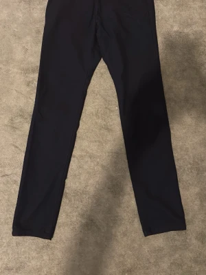 Svarta raka chinos - Snygga svarta chinos med rak passform och klassisk design. Byxorna har diskreta fickor och är tillverkade i ett mjukt tyg som ger en stilren look. Perfekta för dig som gillar enkel och clean stil.