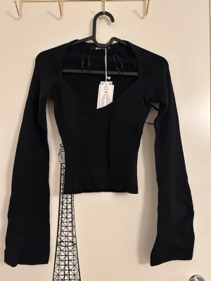 Svart knitted top från Gina Tricot - Svart knitted top med djup v-ringning och figurnära passform från Gina Tricot i storlek XS.  Aldrig använd och har prislappen kvar. Köptes för 399 kr. 