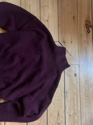 Vinröd stickad tröja från Zara - Mysig vinröd stickad tröja från Zara med hög krage och långa ärmar. Perfekt för kalla dagar och enkel att matcha med jeans eller kjol. Tröjan har en klassisk, rak passform och är tillverkad i ett mjukt material.