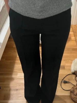 Svarta raka kostymbyxor - Snygga svarta kostymbyxor med rak passform och hög midja. Byxorna har klassisk design med pressveck och diskreta fickor framtill. Perfekta för en stilren look och lätta att matcha med olika toppar.