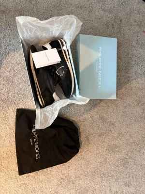 Philippe Model svarta sneakers - Stilrena svarta sneakers från Philippe Model med vita detaljer och logga på sidan. Dom är smutsiga och slitna där av priset!