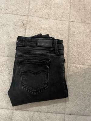 Svarta Replay jeans, slim fit - Säljer ett par svarta Replay jeans med klassisk femficksdesign och diskret Replay-logga på bakfickan. Jeansen har en slim passform och är tillverkade i mjuk bomullsdenim med stretch för extra komfort. Perfekta till en avslappnad streetstyle-look.