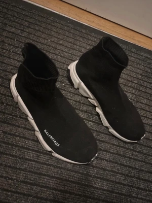 Balenciaga Speed Trainer sneakers - Svarta Balenciaga Speed Trainer sneakers med vit sula och stickad ovandel i textil. Strumpliknande passform med ribbad kant runt ankeln och Balenciaga-logga på sidan. Snygg och futuristisk design som sticker ut.