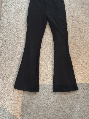 Svarta utsvängda leggings Lindex - Säljer ett par svarta leggings från Lindex med utsvängda ben. De är i stretchigt material och har hög midja. Perfekta för dig som gillar en enkel men trendig look. Storlek 170, passar ca 14 år och uppåt.