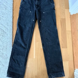 Filippa K Carpenter Jeans  - Jeans med raka ben, låg midja och märken i snickarstil på låren, utan stretch. Extra lång design  Storlek W28  Midja: 38 cm rakt över   Innerbenslängd: 83 cm   NYPRIS: 2700kr